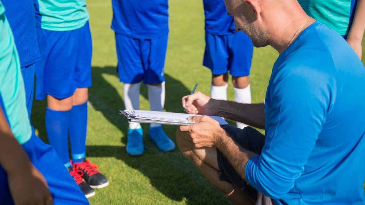 Soccer coach planning strategy with young players on sunny field