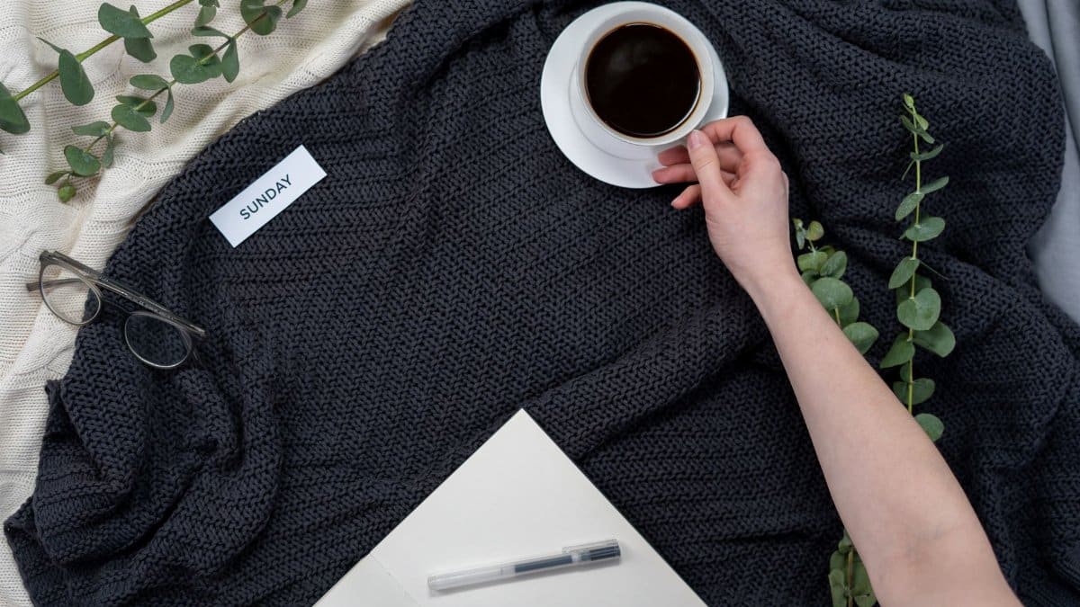 Relaxing Sunday morning setup with coffee, notebook, and glasses on a blanket.