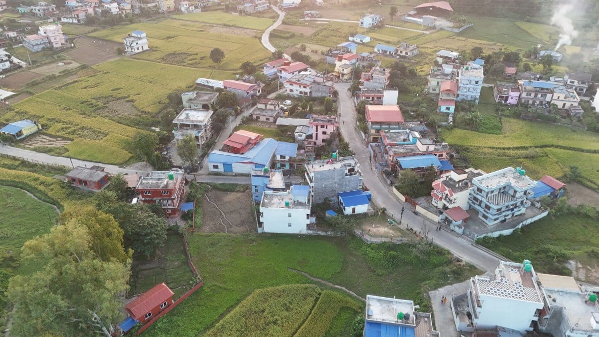 A stunning aerial view of a rural village with colorful rooftops and lush fields in Nepal's countryside.