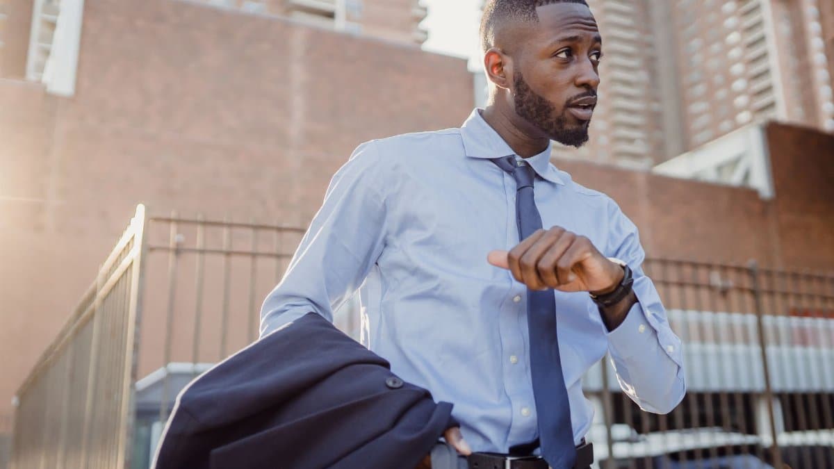Stylish businessman in city street checking the time, wearing suit and tie.