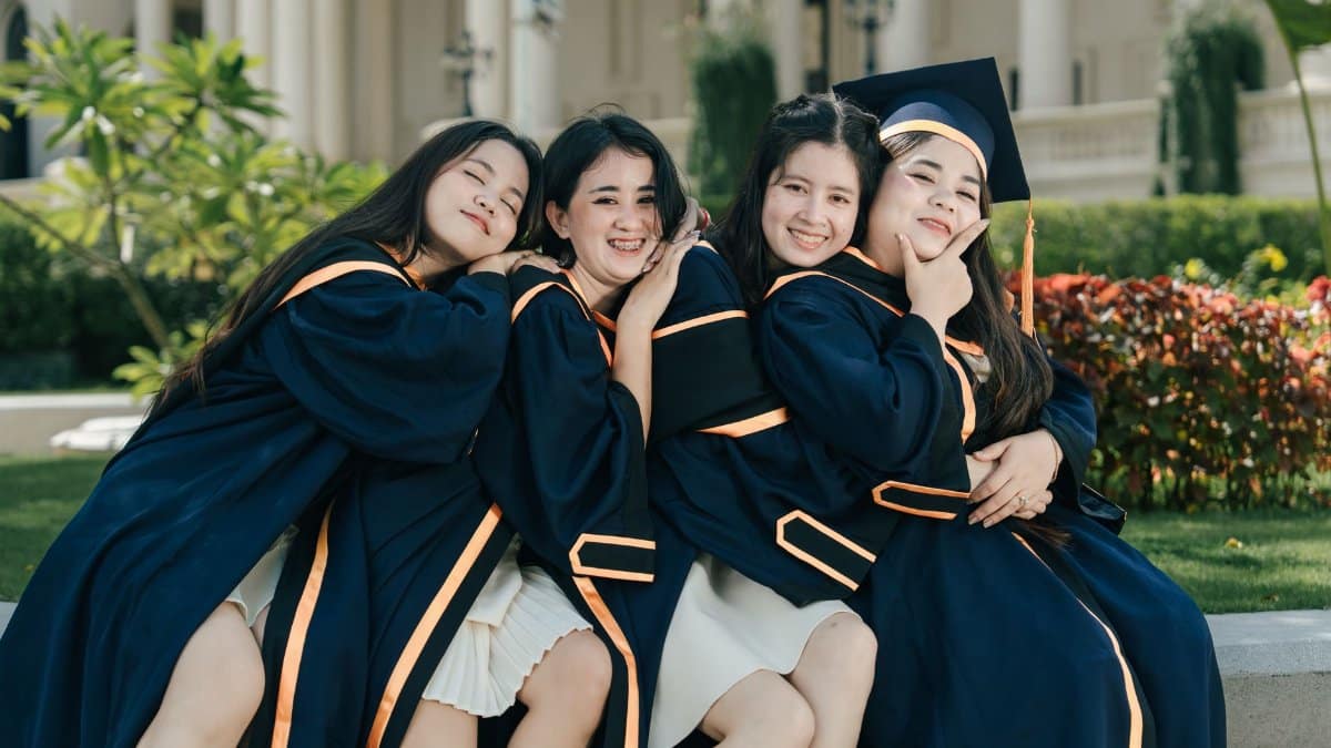 Four female graduates in gowns celebrating their achievement with joy.