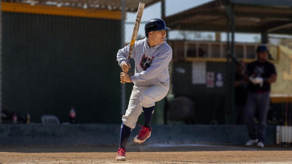 Dynamic image of a baseball player swinging at bat during a daytime game on the field.