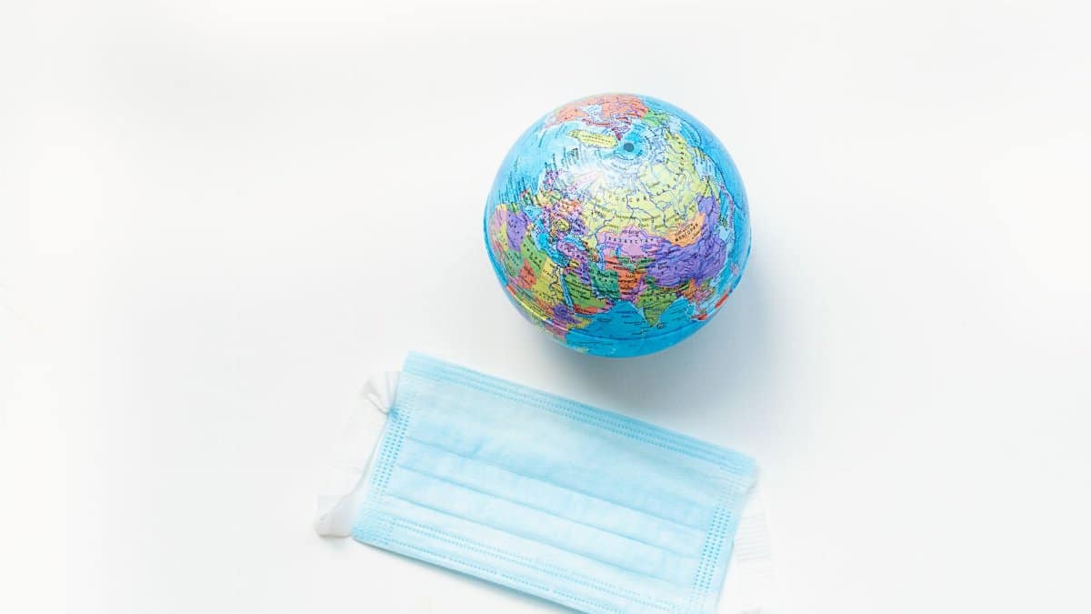 A globe and a face mask symbolizing global health awareness on a white background.