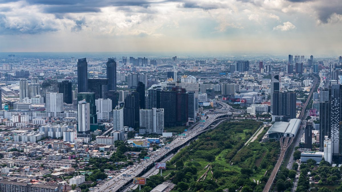 Aerial cityscape showing modern skyscrapers and urban landscape under a cloudy sky.