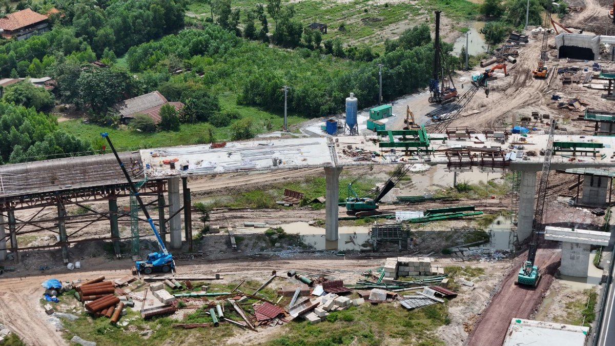 Aerial shot showing the construction of a bridge in a rural area of Vietnam, highlighting the progress and machinery involved.