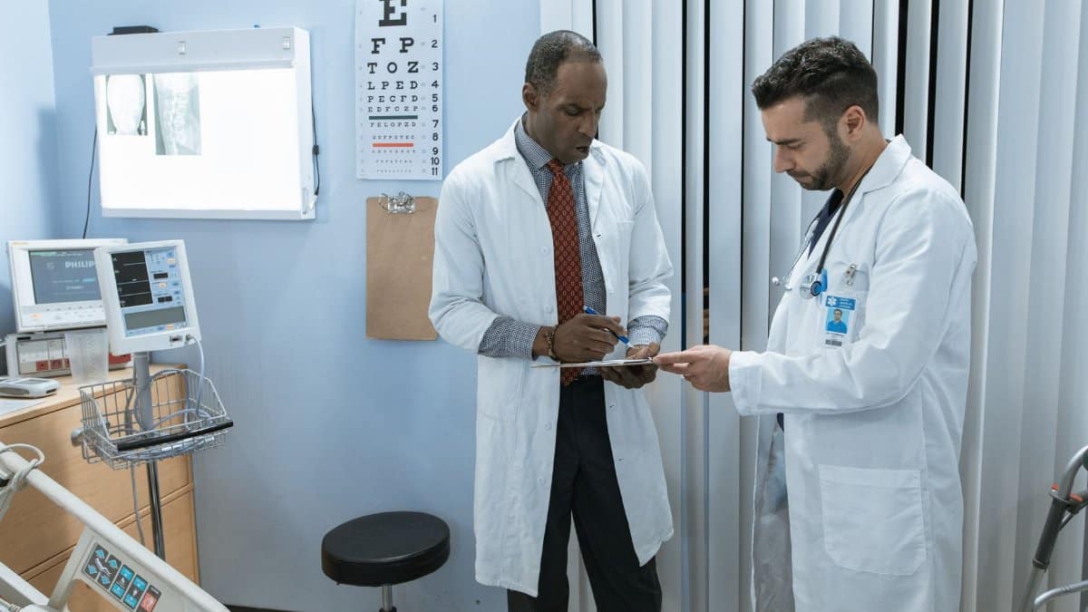 Two doctors in lab coats discussing a patient's medical chart in a hospital setting.