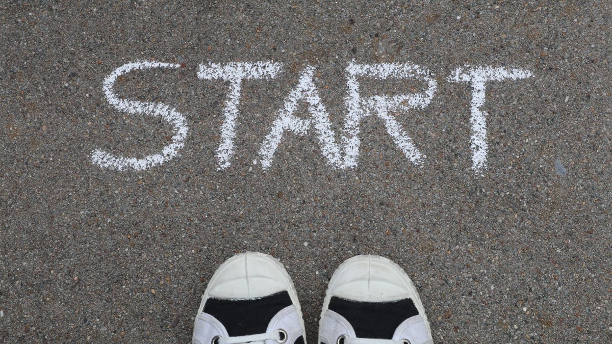Close-up of sneakers and a 'START' chalk drawing on pavement, symbolizing new beginnings.