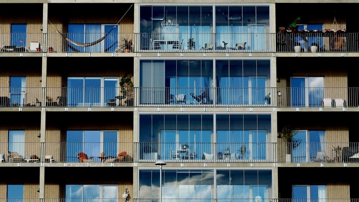 Facade of a modern residential building featuring glass windows, balconies, and metal railings.