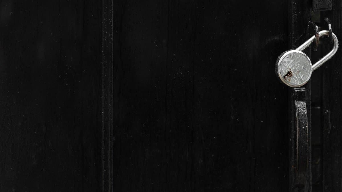 A minimalistic black gate featuring a silver padlock, emphasizing security and secrecy.