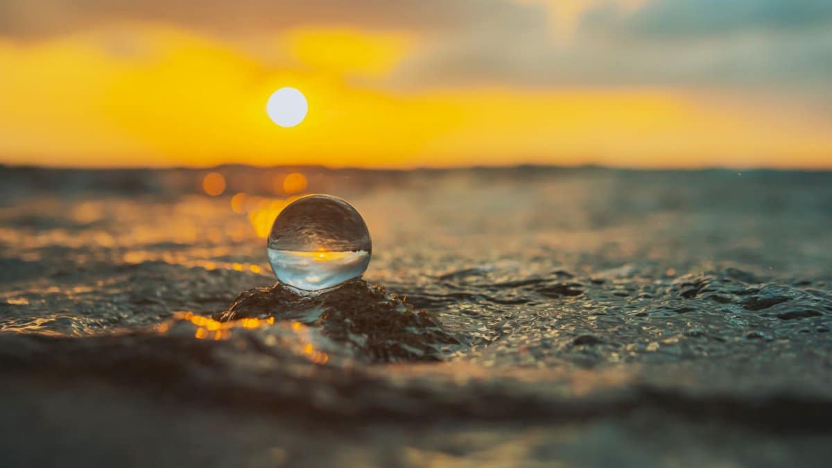 Beach sunset with a crystal ball reflecting waves, creating a golden hue.