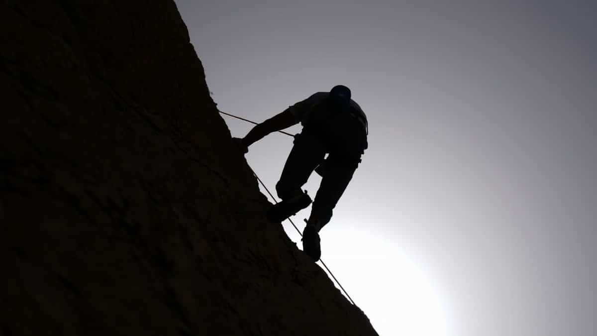 Silhouette of a climber scaling a rocky wall against the rising sun in Damascus, Syria.
