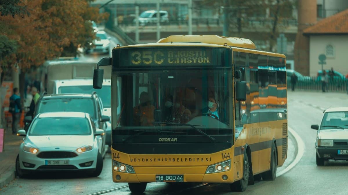 Urban street scene in Bursa, Turkey featuring public transportation bus on a rainy day.