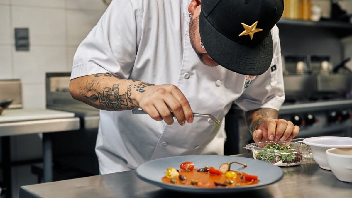 Close-up of a chef in a professional kitchen garnishing a gourmet dish with precision.