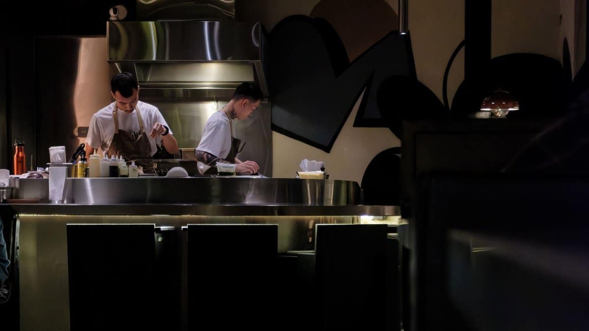 Two chefs working in a modern restaurant kitchen, preparing gourmet dishes under soft lighting.