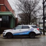 A Chicago police SUV parked on a city street near an intersection on a cloudy day.