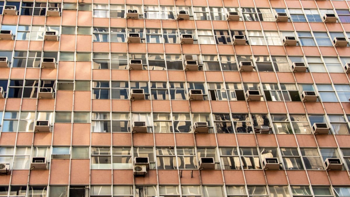Close-up of an urban apartment building facade with multiple windows and air conditioning units.
