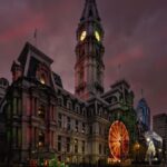 A stunning view of Philadelphia City Hall lit up at night with holiday decorations, including a ferris wheel.