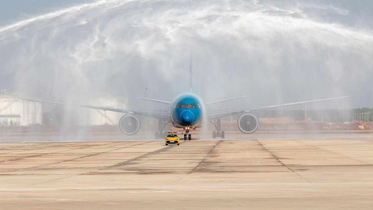 Large aircraft receiving a water salute on the runway with a follow-me vehicle in front.