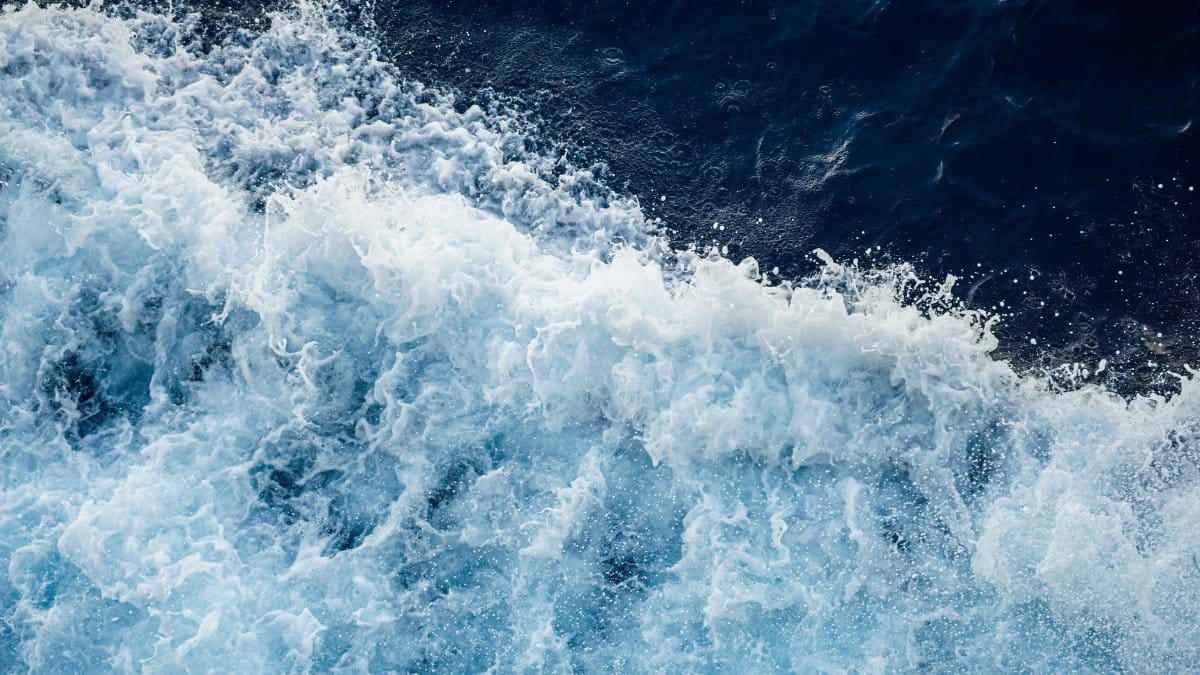 Aerial view of turbulent ocean waves crashing, showcasing natural beauty and power.