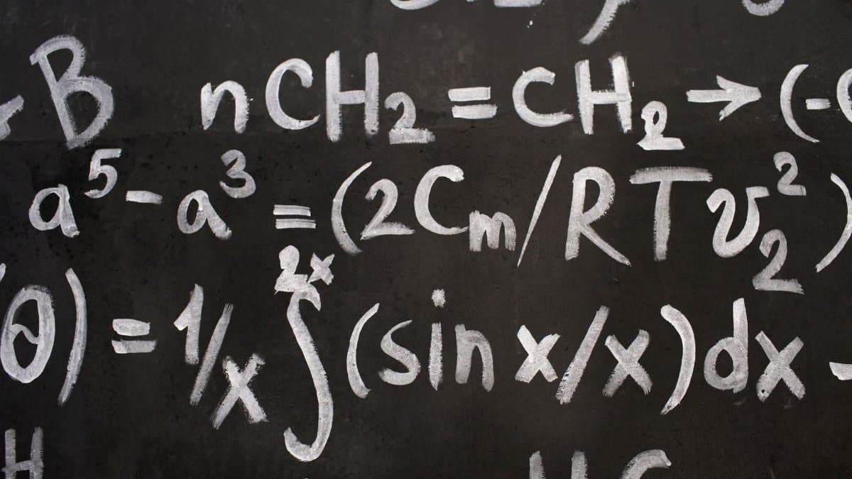 Close-up of complex equations on a chalkboard, showcasing chemistry and math symbols.