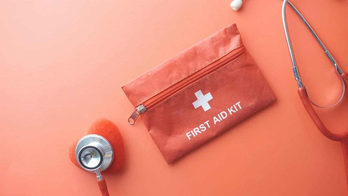 Medical tools including a stethoscope and first aid kit on a pink surface, perfect for healthcare themes.