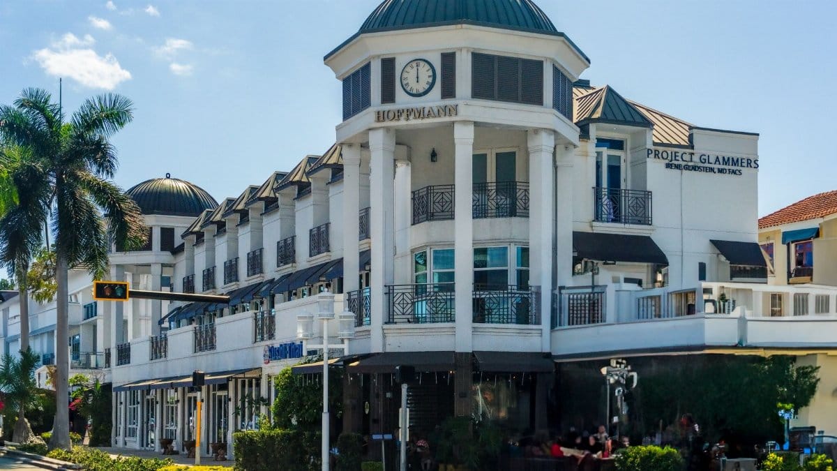 Elegant architecture at a shopping center in Naples, Florida with palm trees and clear skies.