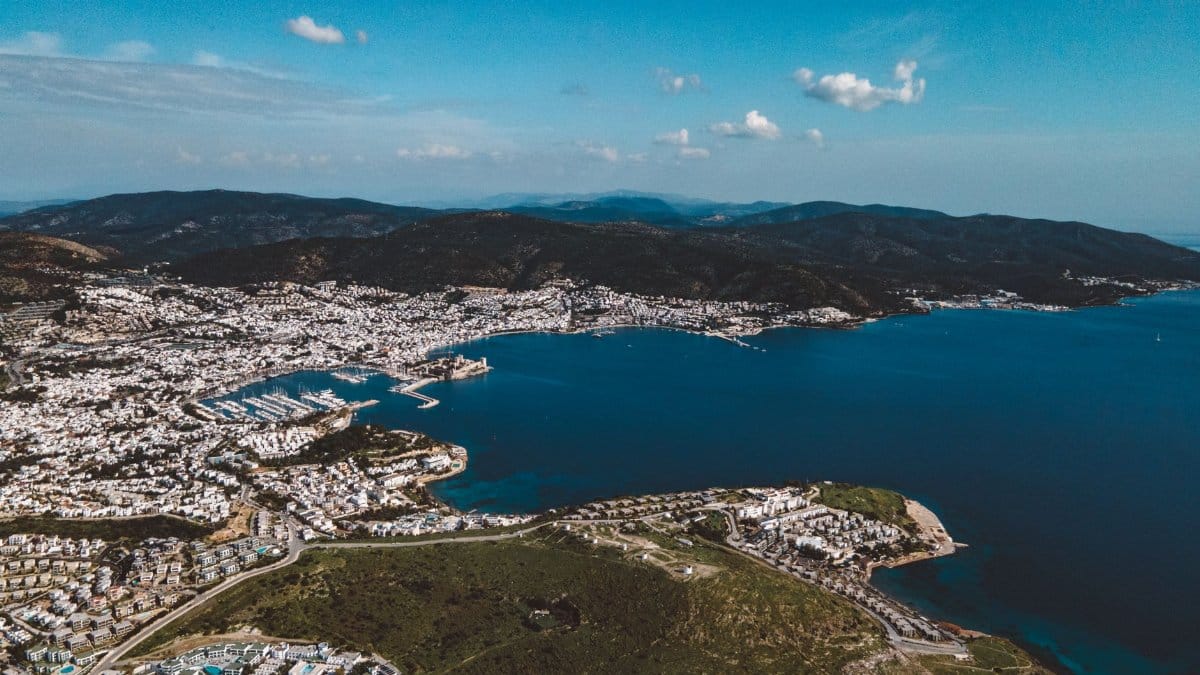 A breathtaking aerial view of a coastal city with a harbor and mountains in the background.