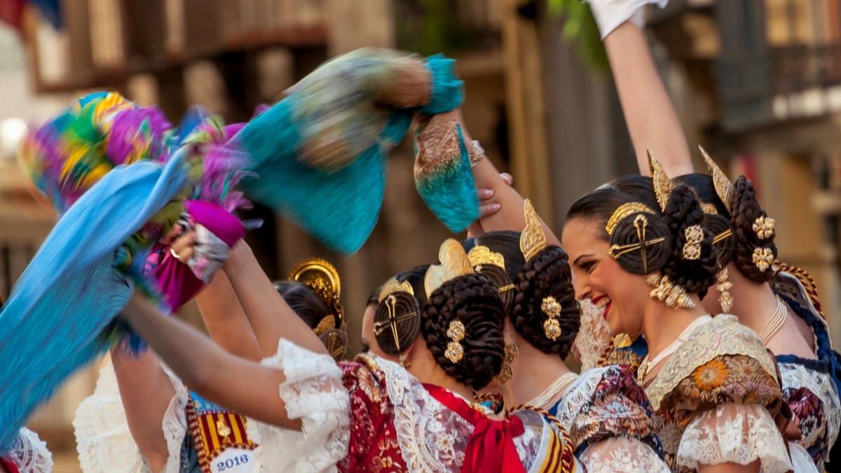 Women in traditional Spanish attire celebrate a cultural festival in Valencia with vibrant dances and festive spirit.