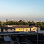 View of Miami skyline from Coral Gables at sunset with residential buildings in foreground.