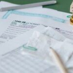 Stack of tax forms and coins with a 'TAX' stamp, symbolizing finance and accounting.