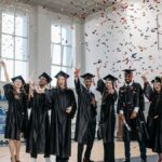 Graduates celebrating with confetti in an indoor sports hall, capturing a joyful moment.