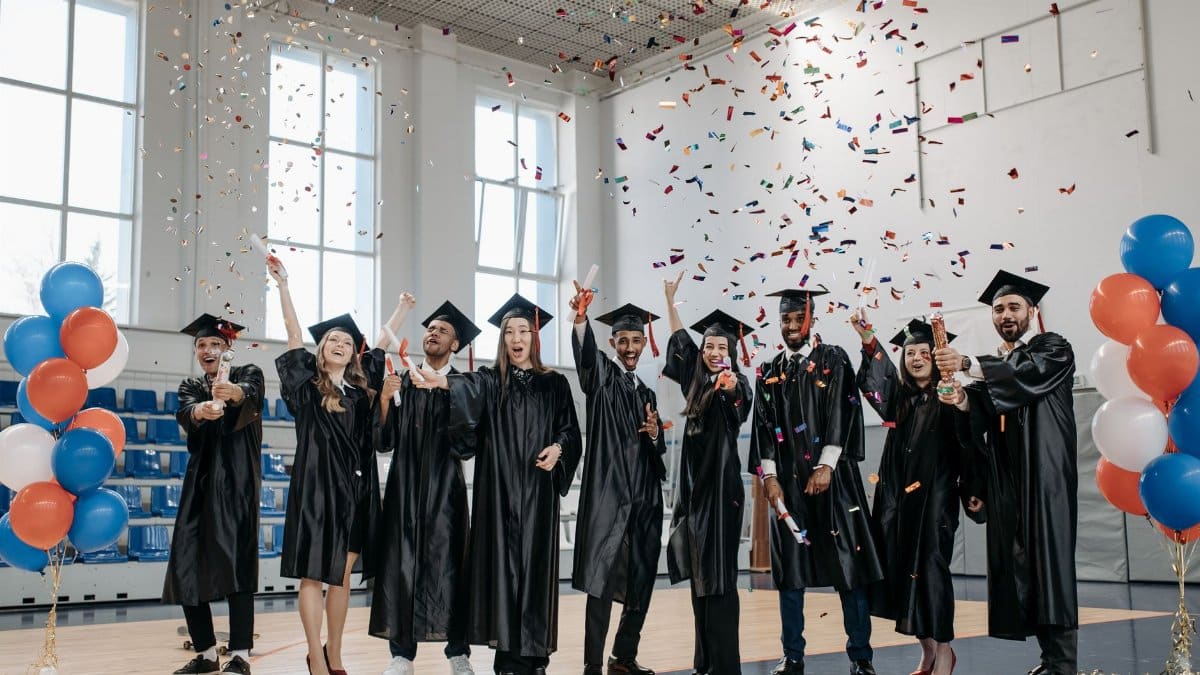 Graduates celebrating with confetti in an indoor sports hall, capturing a joyful moment.