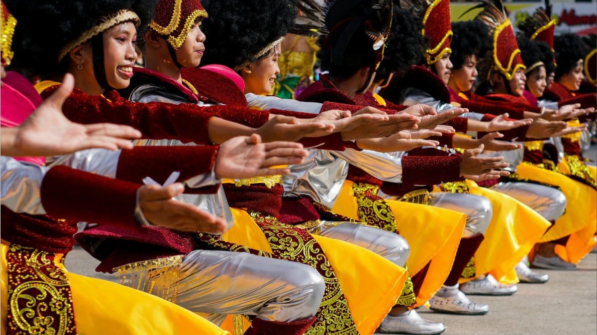 A group of dancers in traditional costumes perform in a vibrant street festival.