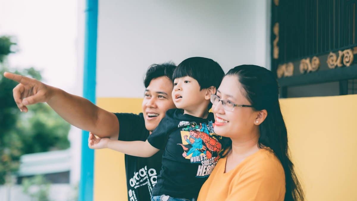 Asian family enjoying togetherness outdoors, pointing at something with smiles.