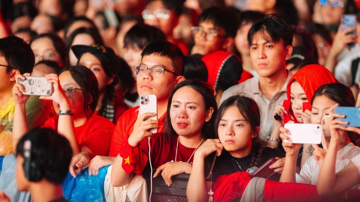 A diverse group of people at an outdoor concert event, engaged and capturing moments.
