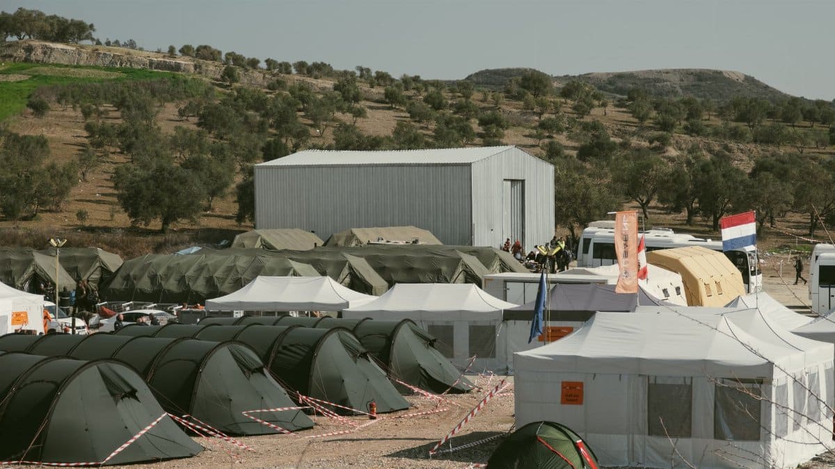 Aerial view of a temporary shelter camp in Antakya, Hatay, Türkiye, surrounded by olive trees.