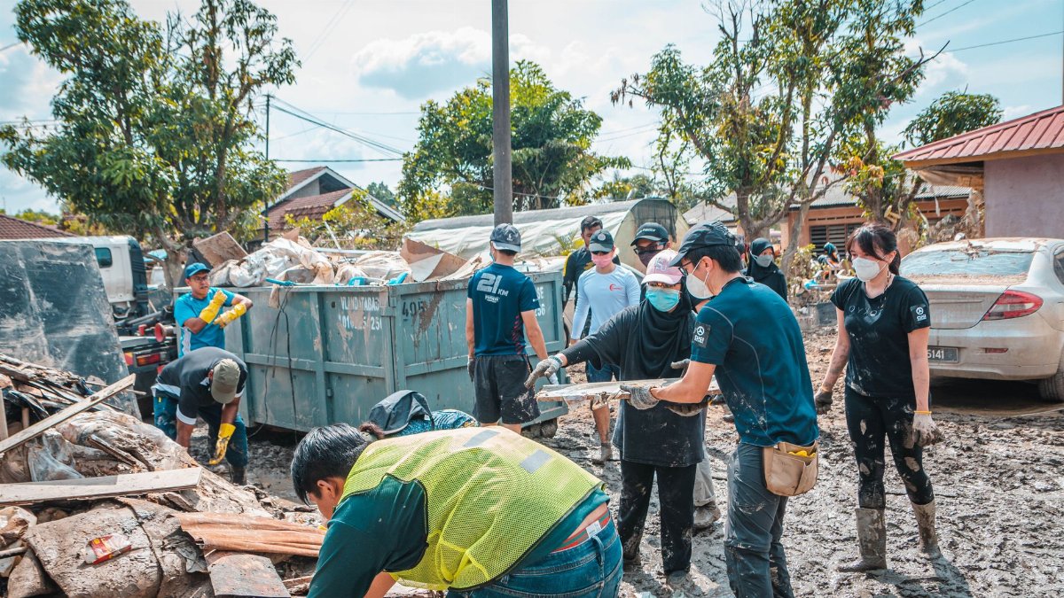 Volunteers work together to clean up debris after a natural disaster, showcasing community effort and teamwork.