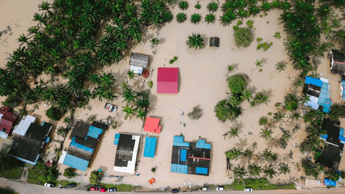Aerial view of a flooded village in Kijal, Malaysia, surrounded by palm trees, illustrating the natural disaster's impact.