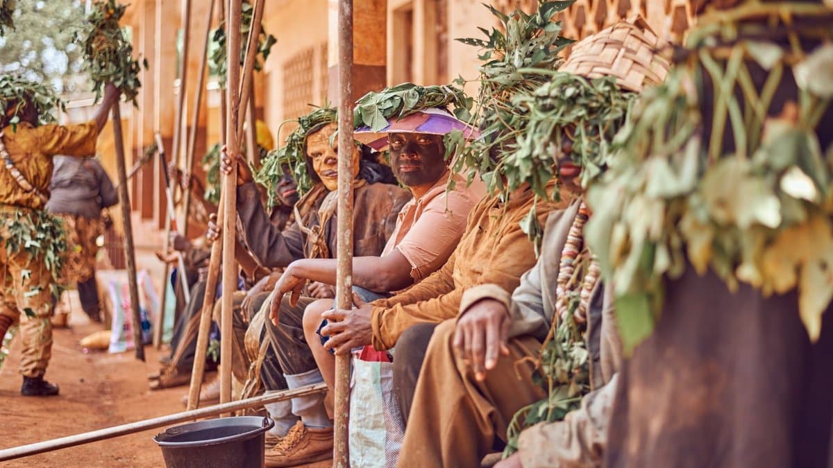 A vibrant African tribal ceremony featuring participants in leaf costumes and traditional attire, celebrating cultural traditions.