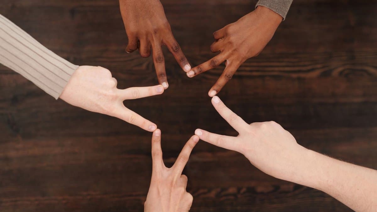 Diverse hands forming a star shape, symbolizing unity and teamwork indoors.