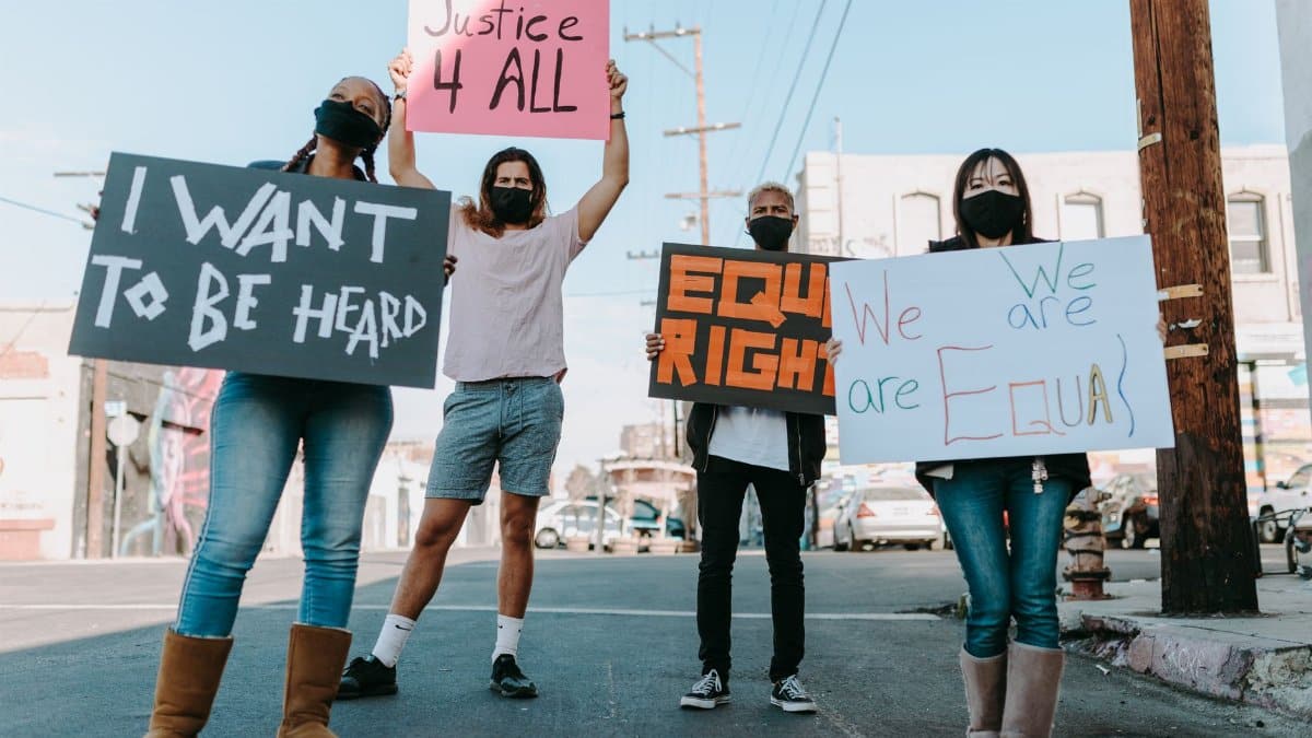 A diverse group holding equality signs during a peaceful protest in an urban setting.