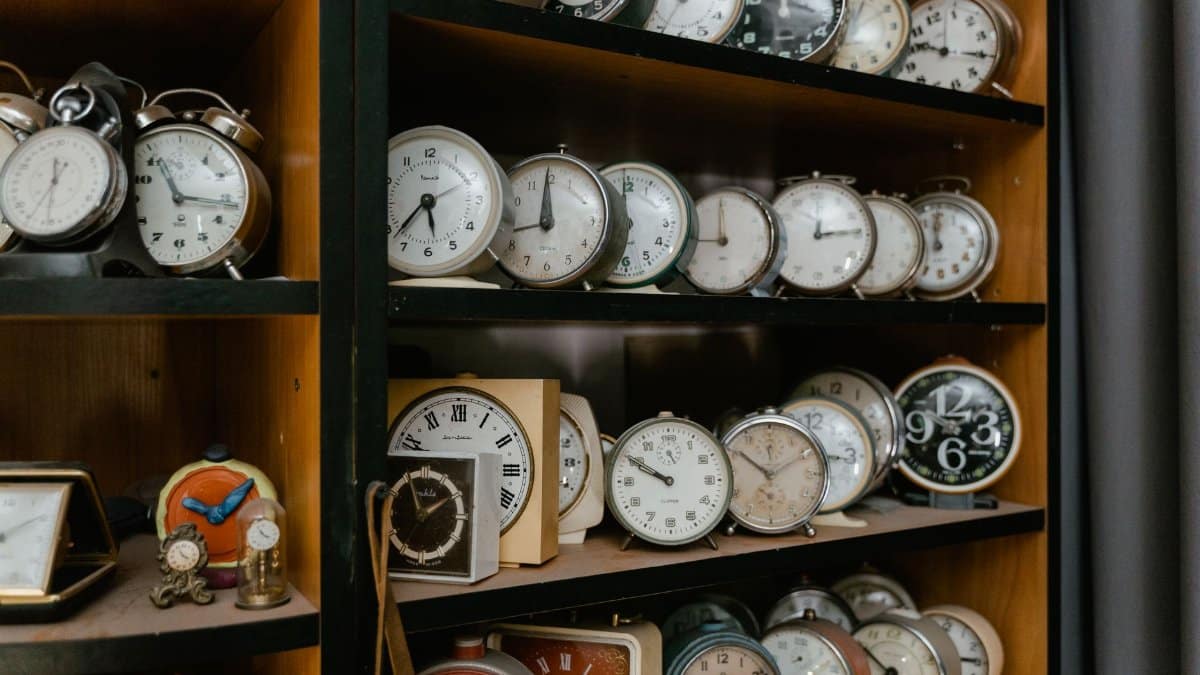 A variety of vintage alarm clocks displayed on wooden shelves, evoking nostalgia.