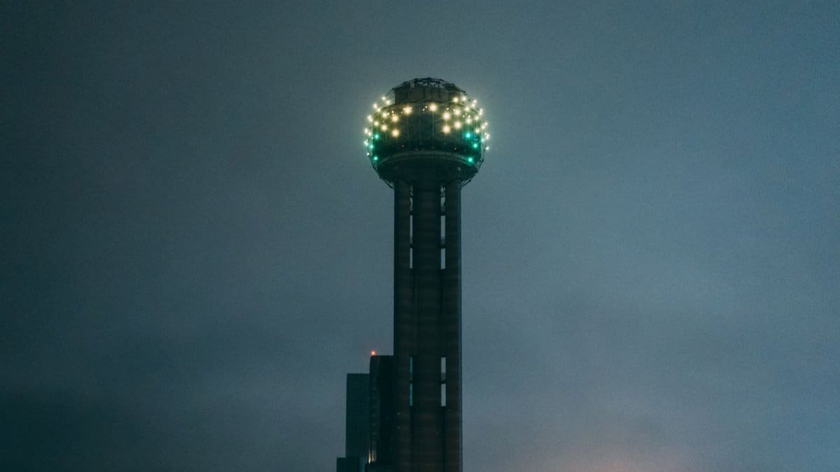 The iconic Reunion Tower glowing vividly during the night in Dallas, Texas.