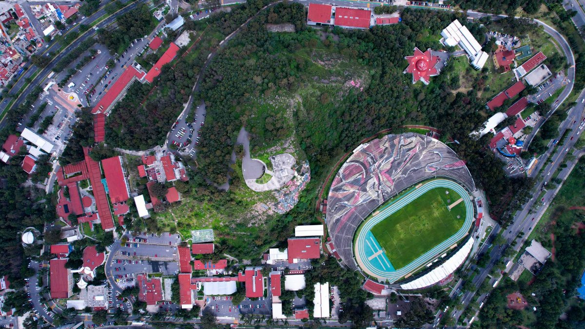 Aerial view of a city stadium encircled by lush greenery and urban architecture.