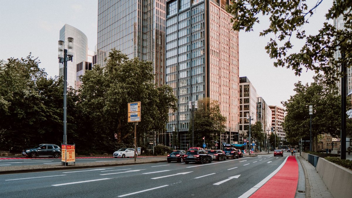 Urban street scene with modern skyscrapers, traffic, and trees on a clear day.