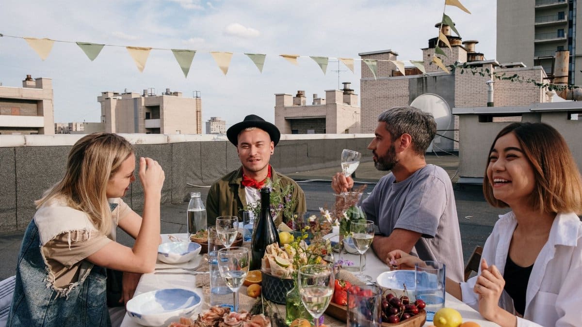 A vibrant rooftop summer gathering with friends enjoying food and drinks.