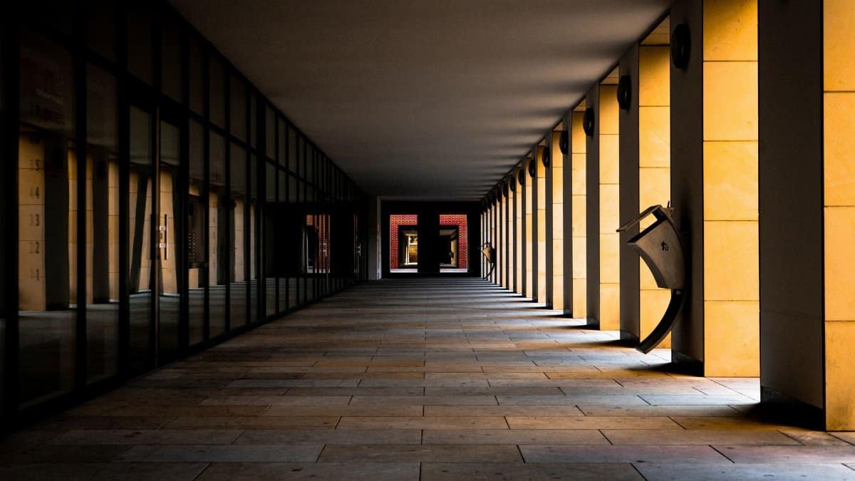 Dramatic view of an empty symmetrical corridor with striking golden columns casting shadows.