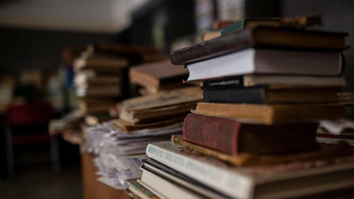 A stack of vintage books in a dim indoor setting, offering a classic and moody atmosphere.