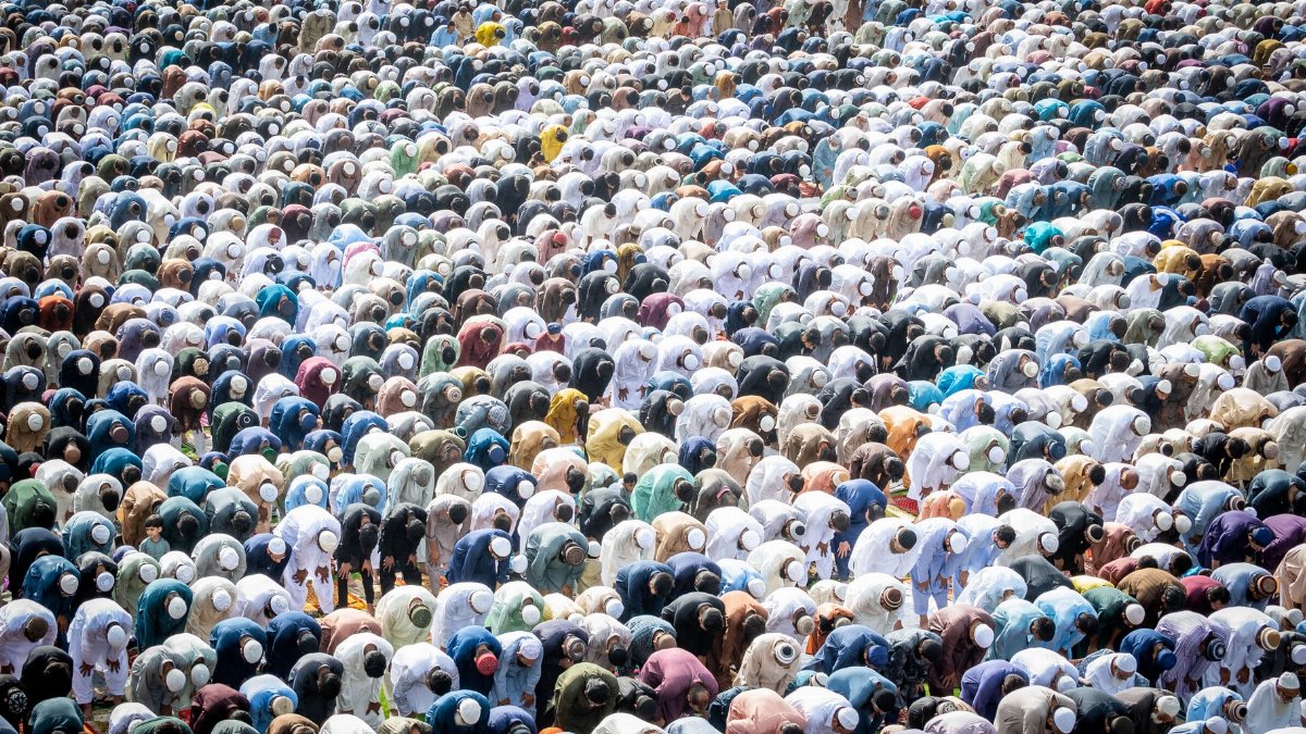 An aerial view of a large group of people bowing in prayer, showcasing unity in religious practice.