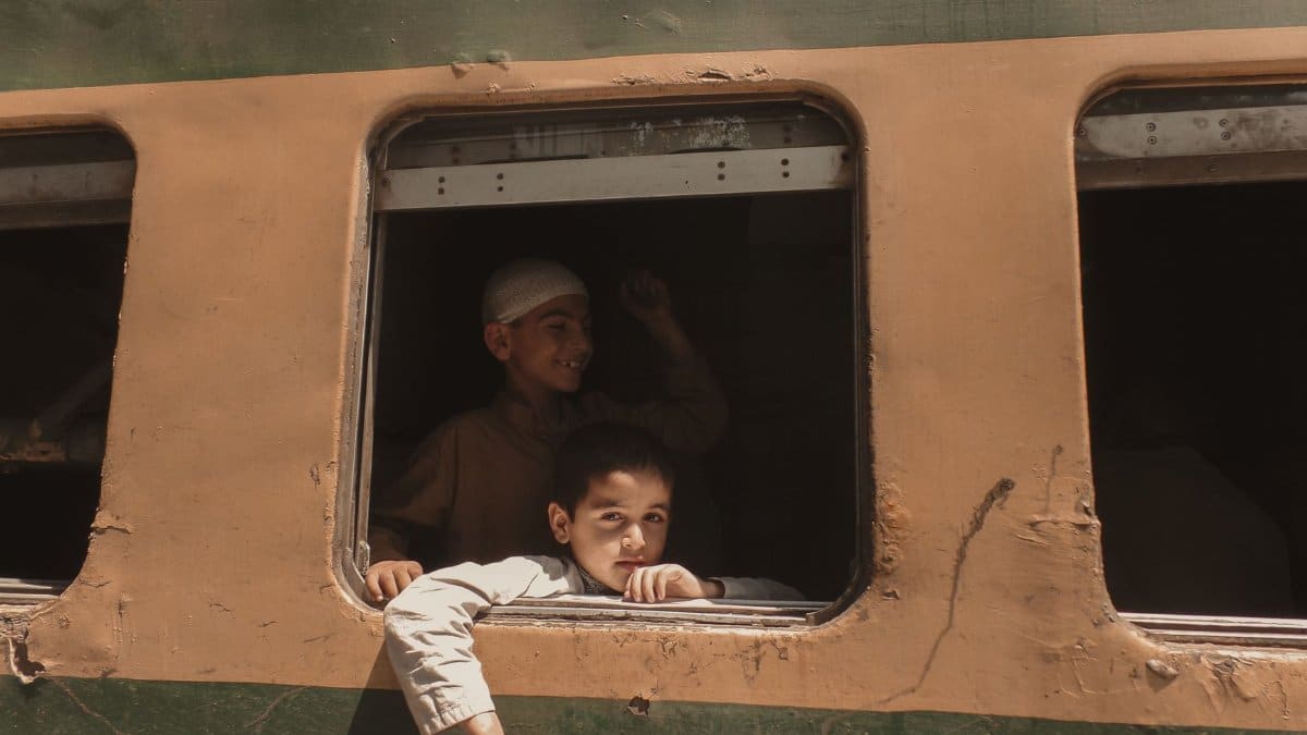 Two boys peering out of a train window, capturing a moment of travel and curiosity.
